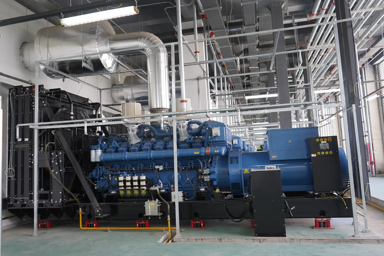 Large diesel generator integrated with ventilation, exhaust and electrical systems inside a plant room
